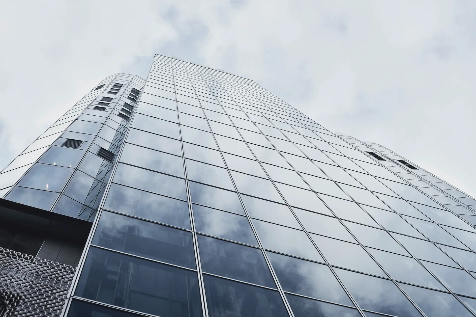 Torre de oficinas de cristal que refleja un cielo nublado